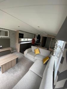 a living room with a white couch and yellow pillows at 17 Wildflower Meadow in Chapel Saint Leonards