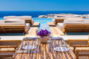 a table with glasses and a vase of purple flowers on it at Tropicana Hotel , Suites & Villas Mykonos in Paradise Beach