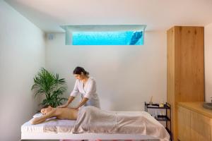 a woman giving a man a massage on a bed at Tropicana Hotel , Suites & Villas Mykonos in Paradise Beach