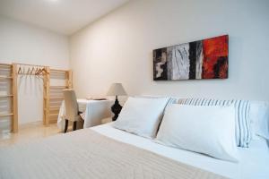 a white bedroom with a bed and a table at Acogedor Apartamento José Laguillo. in Seville