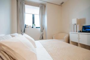 a white bedroom with a bed and a window at Acogedor Apartamento José Laguillo. in Seville