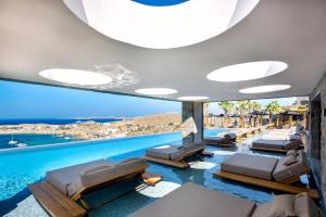 a pool with lounge chairs and a view of the ocean at Tropicana Hotel , Suites & Villas Mykonos in Paradise Beach