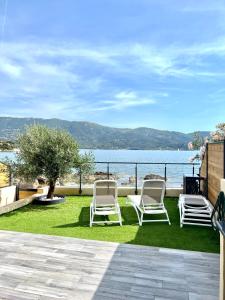 a group of chairs sitting on the grass near the water at PIEDS DANS L'EAU, TIUCCIA, appartement 2-4 pers in Casaglione