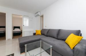 a living room with a gray couch and yellow pillows at Apartmani Čanaki Supetar in Supetar