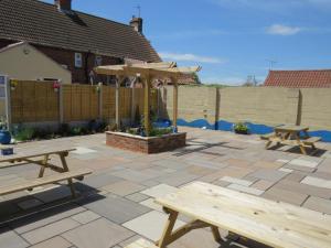 a patio with two picnic tables and an umbrella at The Stables At Eastmoor Farm in Bridlington