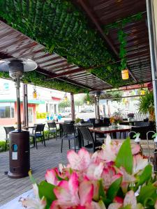un patio con mesas, sillas y flores rosas en Quindeloma Art Hotel & Gallery en Riobamba