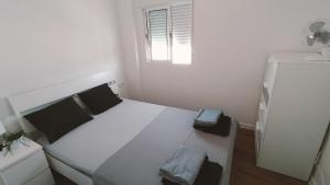 a small white bedroom with a bed and a window at Apartamento Aguilera in Gandía