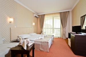 a hotel room with two beds and a television at Saint George Palace Hotel All-inclusive in Sveti Vlas +66 photos