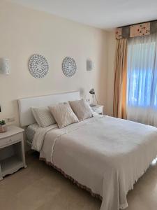- une chambre blanche avec un grand lit et une fenêtre dans l'établissement Estrelicia II, à Marbella