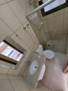a bathroom with a sink and a toilet and a mirror at Golfinho Plaza Hotel in Cananéia