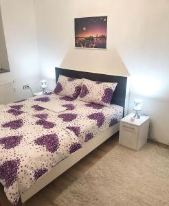 a bedroom with a bed with a purple and white comforter at Apartman Dunja II in Prijedor