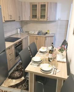 a kitchen with a wooden table with chairs and a dining room at Apartman Dunja II in Prijedor +16 photos
