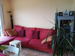 een rode bank in een woonkamer met een plant bij Pis a Blanes amb precioses vistes al mar. in Blanes
