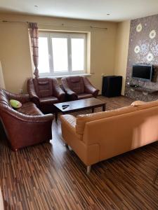 a living room with leather couches and a tv at Villa Bodiky in Bodíky