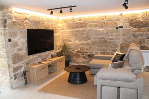 a living room with a stone wall with a tv at CASA VACACIONAL ACIO in Ourense