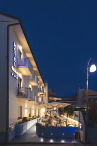 a hotel with tables and chairs in front of it at night at Hotel Nina in Marina di Bibbona