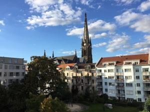 um edifício com uma torre de igreja ao fundo em Petersweitblick-Bayerischer Bahnhof em Leipzig