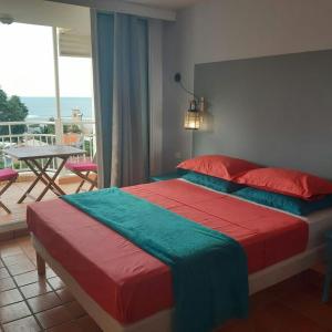 a bedroom with a bed and a balcony with a table at Les Studios de la Baie 246 in La Trinité