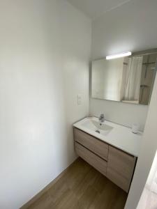 a white bathroom with a sink and a mirror at Chambre d'hôtes près de la plage in Pornichet