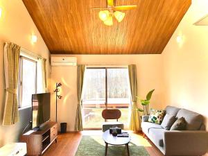 ein Wohnzimmer mit einem Sofa und einem TV in der Unterkunft Yatsugatake Villa Masaki - Vacation STAY 74331v in Hokuto