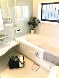 ein Badezimmer mit einer Badewanne und einer Pflanze auf dem Boden in der Unterkunft Yatsugatake Villa Masaki - Vacation STAY 74331v in Hokuto