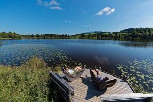 two people laying in hammocks on a dock on a lake at Alpinlife Ferienhaus in Bad Kohlgrub