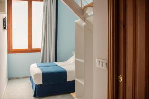 um pequeno quarto com uma cama e uma janela em Ad Hoc Carmen em Valência
