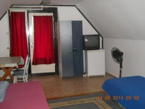 ハイドゥソボスローにあるFenyves Nyaralóのリビングルーム(赤いカーテン、テレビ付)