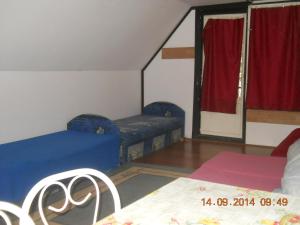 ハイドゥソボスローにあるFenyves Nyaralóのベッド2台、赤いカーテン付きの窓が備わる客室です。