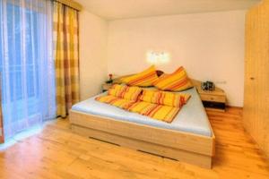 1 dormitorio con 1 cama con almohadas de color naranja y amarillo en Appartements Avenzio, en Sölden