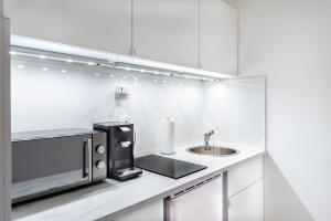 a white kitchen with a sink and a microwave at GelsenDesign III - Netflix I Balkon I Zentral in Gelsenkirchen