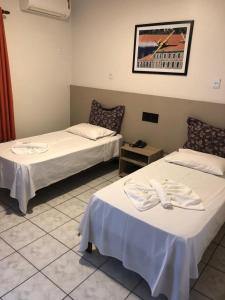 a room with two beds and a table at Limeira Plaza Hotel in Limeira