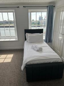 a bed in a room with two windows at Spacious One Bedroom Flat with River View, 1E in Great Yarmouth