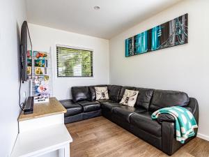 uma sala de estar com um sofá de couro preto em Mountain Magic - Ohakune Holiday Home em Ohakune