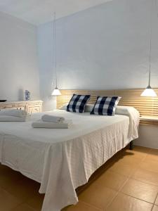 1 dormitorio con 1 cama blanca grande con almohadas azules y blancas en Can Brilla, en Sant Francesc Xavier