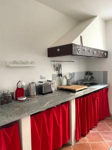 a kitchen with a counter top with red curtains at Il Fienile in Garessio