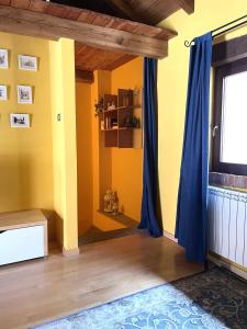 a room with yellow walls and blue curtains at Il Fienile in Garessio