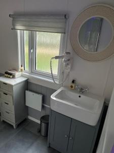 a bathroom with a sink and a mirror and a window at The Cozy Cub in Romsey