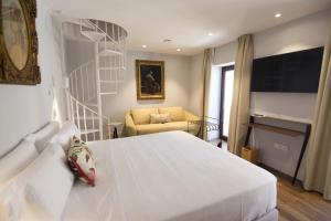 a bedroom with a white bed and a chair at Hotel Oleum - Parking Gratuito Reserva Previa in Andújar