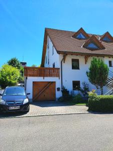 une voiture garée devant une maison blanche dans l'établissement Apartment Entegast, à Schopfheim