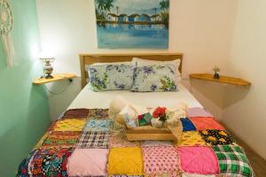 a bed with a quilt and a basket of flowers on it at Pousada São Miguel Filosofal in São Miguel do Gostoso