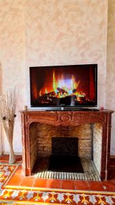 a fireplace with a television on top of it at Chez Dédou et Madou in Florensac