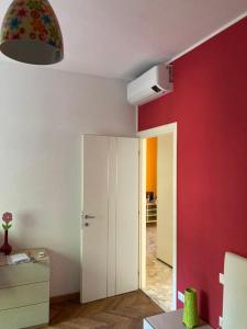 Cette chambre est dotée d'un mur rouge et d'une porte blanche. dans l'établissement Youhome Millelire Apartment, à Milan