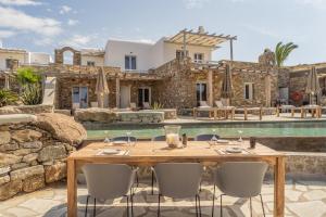 a wooden table and chairs in front of a villa at ELA Boutique Hotel & Spa in Elia Beach