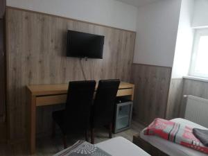 a room with a desk with two chairs and a television at Twins in Hurbanovo