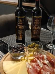deux bouteilles de vin et une assiette de viande et de fromage dans l'établissement Penthouse Apartman Marčelina in Trogir, à Trogir