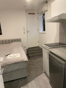 Luton Short Term Lets - Cardiff Road في لوتون: غرفة نوم صغيرة بها سرير ومطبخ