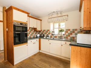 a kitchen with white cabinets and a sink at The Wain House in Acton Scott