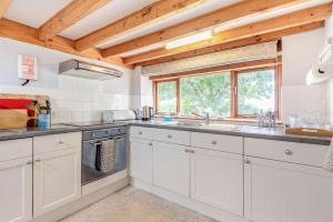 a kitchen with white cabinets and a window at Tryfan Cottage in Caeathro