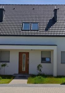 een wit huis met een bruine deur en ramen bij Baltic 51 - TRZĘSACZ SUNNY SIDE BALTIC in Trzęsacz